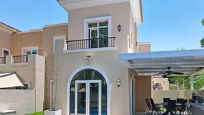 Une maison à deux étages dotée d’un patio, d’un espace salon extérieur et d’une piscine.