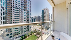 A balcony with a view of high-rise buildings, a clear sky, and a parking area below. - Calm 1 Bedroom l Free Wi-Fi l Stunning Marina View (Dubai)