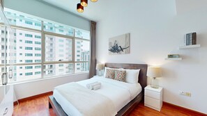 A hotel room with a large window, a bed with white linens, a wooden floor, a nightstand with a lamp, and a wall-mounted shelf with a book. - Calm 1 Bedroom l Free Wi-Fi l Stunning Marina View (Dubai)