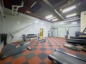 Een fitnessruimte met loopbanden, krachtapparaten en losse gewichten.