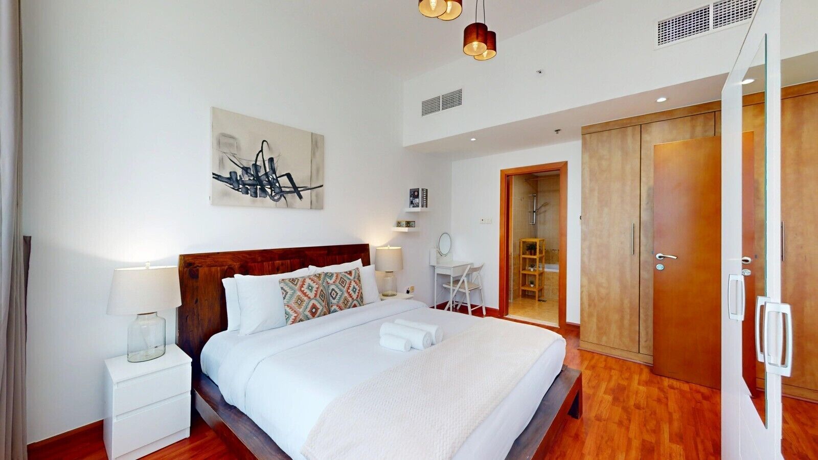 Une chambre d’hôtel moderne avec un grand lit, des tables de chevet, un bureau et une armoire.