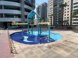 An outdoor swimming pool with a blue mosaic design, surrounded by a tiled deck. - Calm 1 Bedroom l Free Wi-Fi l Stunning Marina View (Dubai)
