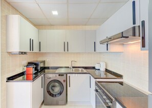 Une cuisine compacte équipée d’un lave-linge, d’un four à micro-ondes et d’appareils électroménagers en acier inoxydable.