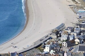 A coastal town with a beach, houses, and a road.