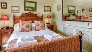 A hotel room with a large bed, two bedside tables, a mirror, and framed pictures on the walls. - Boatswains Watch, Sleeps 4, Pet Friendly (Portland)