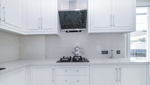 Una cocina moderna con armarios blancos, una estufa negra y un ventanal con vistas al exterior.