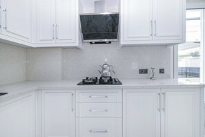 A modern kitchen with white cabinetry, a black stove, and a window providing a view of the outside.