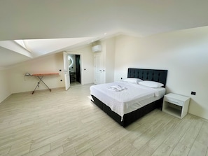 Une chambre à coucher avec un lit, une table de chevet, une petite table et une lucarne.