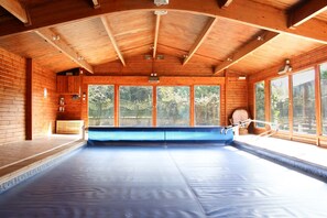 Una cabaña de madera con un ventanal grande, una bañera azul y techo de madera.
