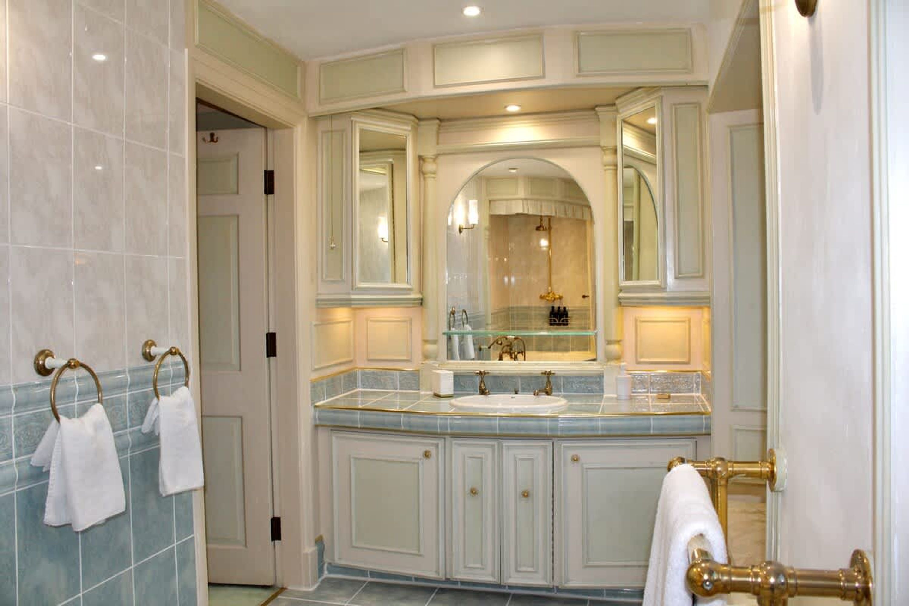 A bathroom with a large mirror, a sink, and a toilet.