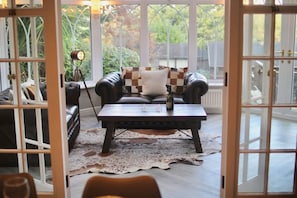 Habitación con sofá de cuero, una mesa de centro y vista a zonas verdes a través de amplios ventanales.