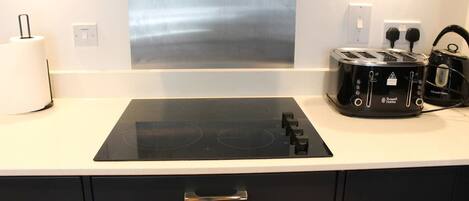 Une cuisine moderne équipée d’une plaque de cuisson à induction noire, d’un grille-pain et d’une bouilloire.