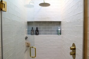 A shower with a handheld showerhead, a towel rack, and a shelf with toiletries. - Lewes Sauna House Characterful Interiors Castle Views (Lewes)