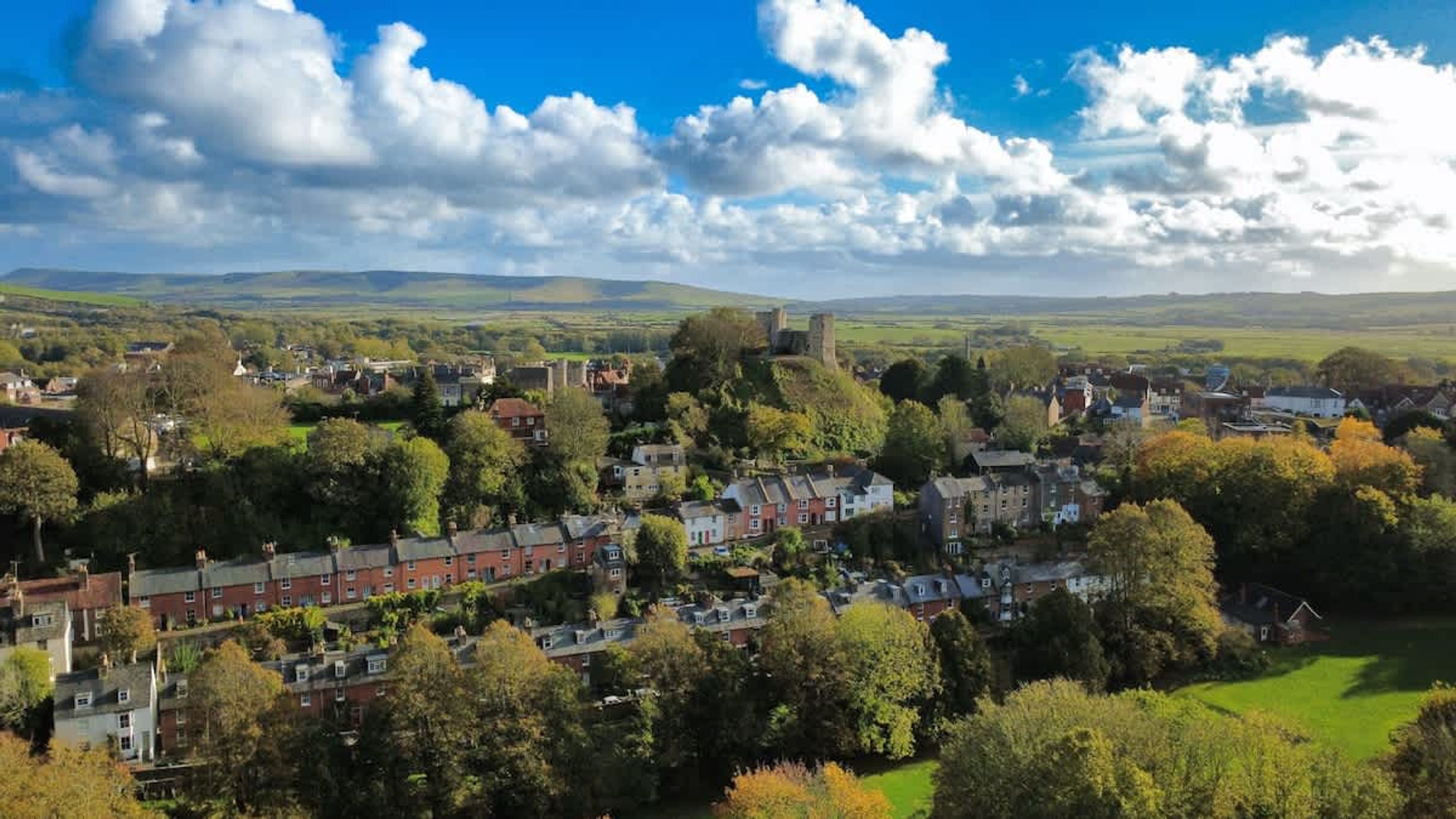 A town with historic buildings, a castle, and a green landscape.