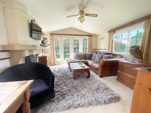 Ein gemütliches Wohnzimmer mit Sofa, Couchtisch, Fernseher und Deckenventilator.