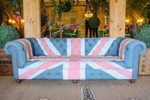 Ein geschnürtes Sofa mit Union-Jack-Muster, platziert in einem Raum mit Holzwänden und Pendelleuchten.