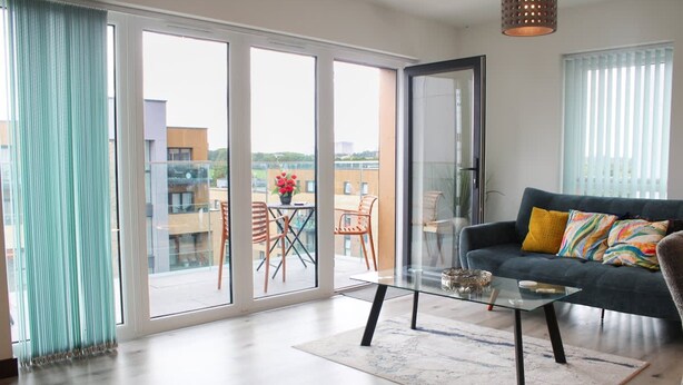 Una sala de estar moderna con un sofá, una mesa de centro de vidrio y vistas a un patio exterior a través de amplios ventanales correderas.