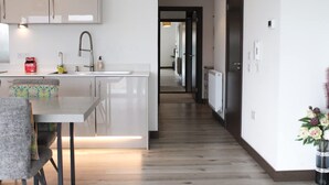 Una cocina moderna con armarios blancos, un lavamanos de acero inoxidable y un comedor con mesa y sillas.