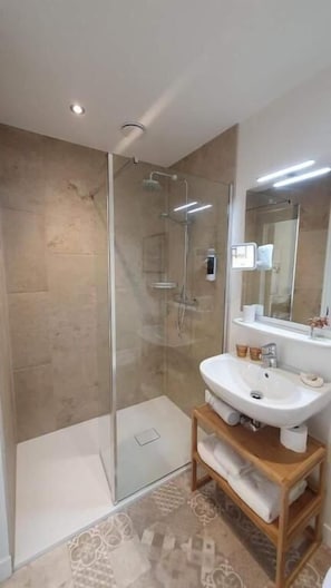A modern bathroom with a glass shower enclosure, a white sink, and a wooden vanity. - Le Rodin Bazas (BAZAS)