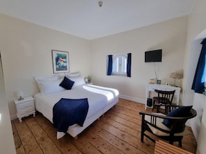 A bedroom with a bed, bedside table, chair, TV, window, and artwork. - Le Rodin Bazas (BAZAS)