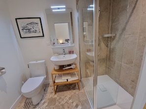 A modern bathroom with a toilet, sink, and glass-enclosed shower.
