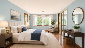 Een slaapkamer met een bed, nachtkastjes, een dressoir, een stoel en een spiegel.