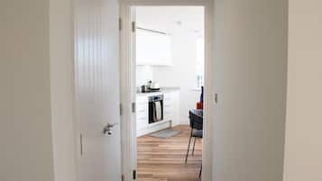 A modern kitchen with white cabinetry, a built-in oven, and a dining area with a chair.
