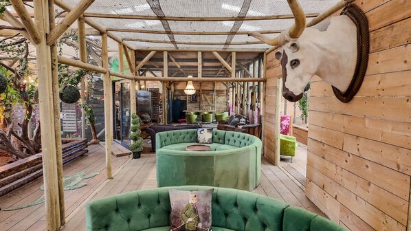 A rustic wooden structure with a green cushioned seating area and a mounted animal head.