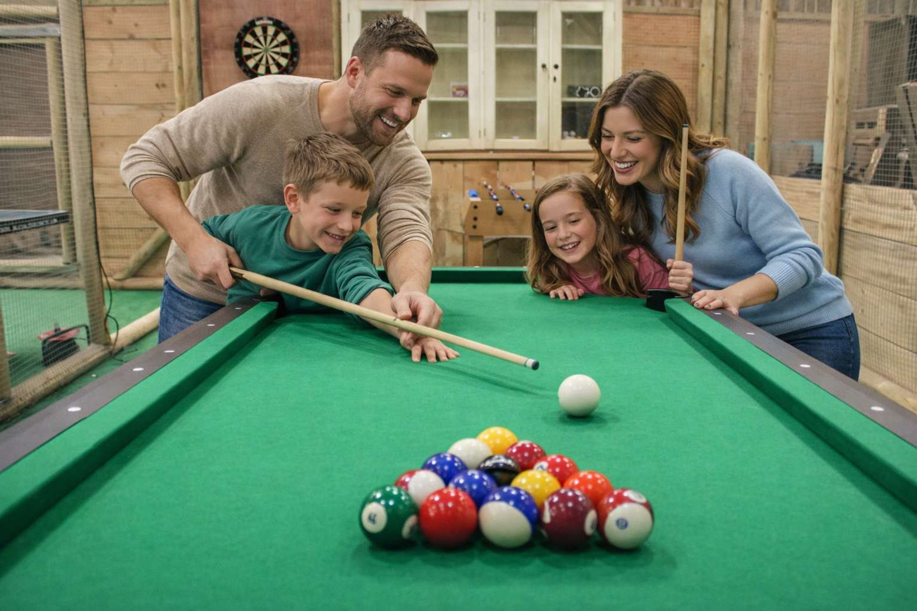 A pool table with balls, a dartboard, and cabinets in the background.