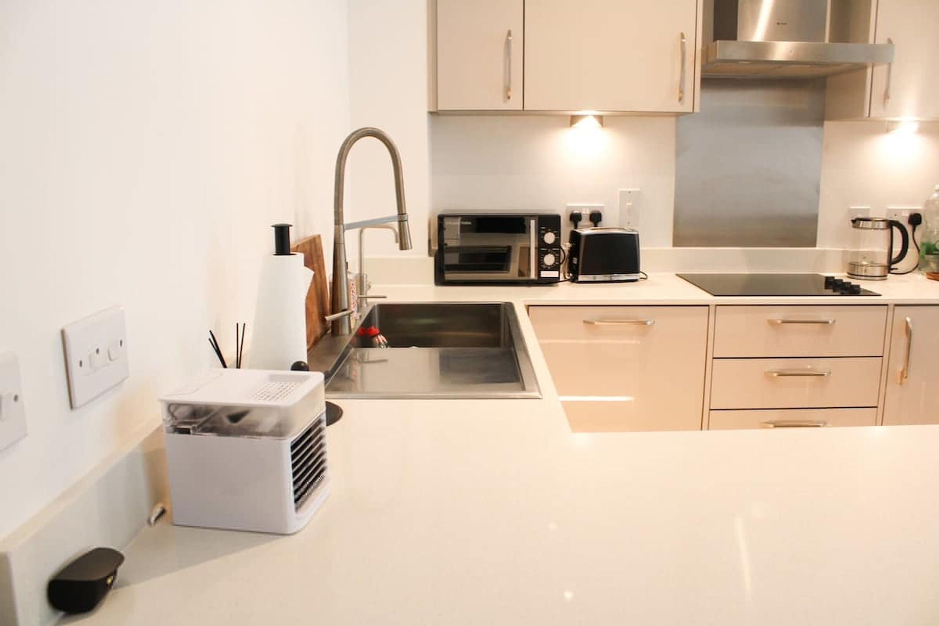 A modern kitchen with a stainless steel sink, a microwave, a toaster, and a coffee maker.