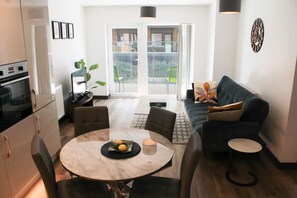 A modern living room with a round marble table, a dark green sofa, and a dining area with chairs. - The Ivy Abode Stylish 2-bed Apartment Parking (Harlow)