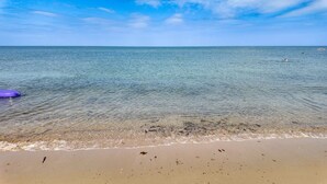 A beach with clear water, a sandy shore, and a distant ship. - Luxury Sea View Home With Hot Tub Sauna (Llanerchymedd)
