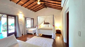 A bedroom with a canopy bed, two bedside tables, a large window, and a ceiling fan. - Spacious house in a large, tranquil walled garden. Close to everything. (Trancoso)