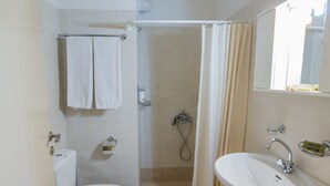 A bathroom with a toilet, shower, and sink.