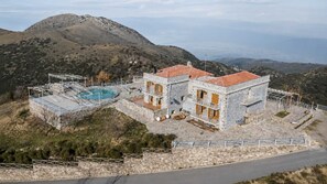 A stone building with a swimming pool, a balcony, and a view of the surrounding hills. - Faris Hotel - Cozy Triple Room Near Sparta (Sparta)