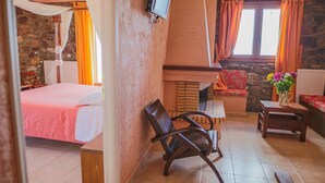 A bedroom with a bed, a chair, a small table, a TV, and a window with curtains. - Faris Hotel Taygetos Comfy Suite Near Sparta (Sparta)