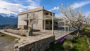 A stone building with a balcony, surrounded by mountains and flowering trees. - Faris Hotel Taygetos Comfy Suite Near Sparta (Sparta)