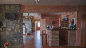 Una cocina amplia con pared de piedra, una isla de ladrillo y una zona de comedor con sillas.