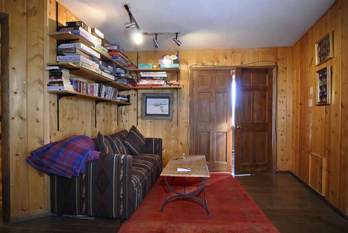 Ein Zimmer mit Holzwänden, einer Couch, einem Tisch und einem Bücherregal voller Bücher.