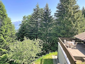 Eine Terrasse mit Gartenmöbeln, umgeben von dichter Vegetation und Blick auf die Berge.
