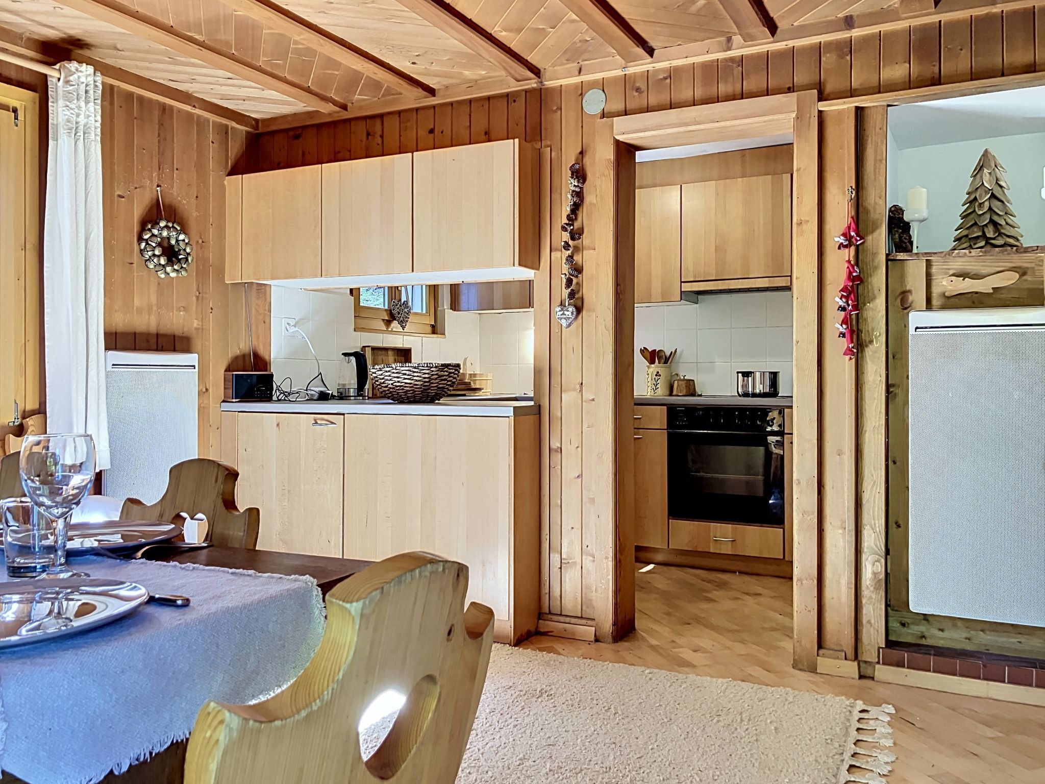 Un intérieur en bois comprenant une table à manger, une cuisine avec des meubles en bois et une vue sur la pièce adjacente.