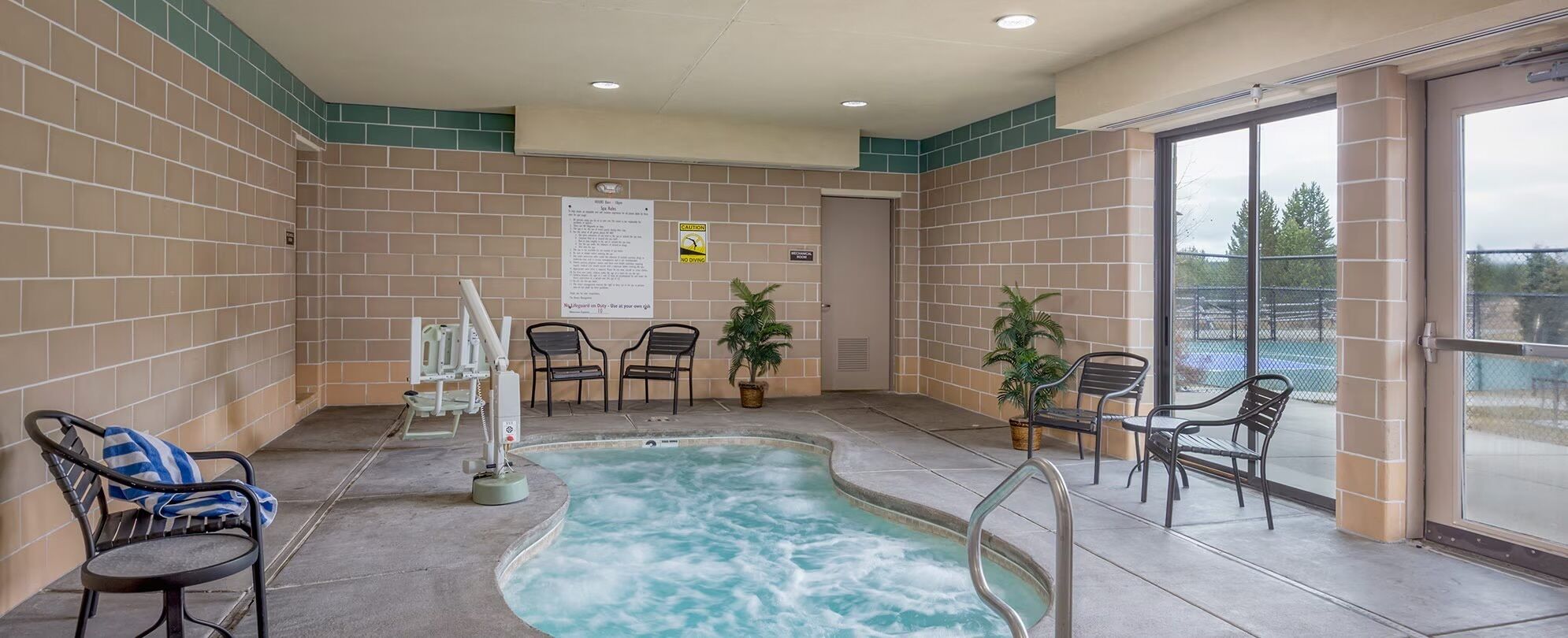 A hot tub area with a pool, chairs, and a sign on the wall.