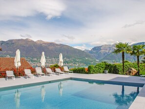 Una piscina amb gandules i ombrelles, amb vista a un paisatge de muntanyes.