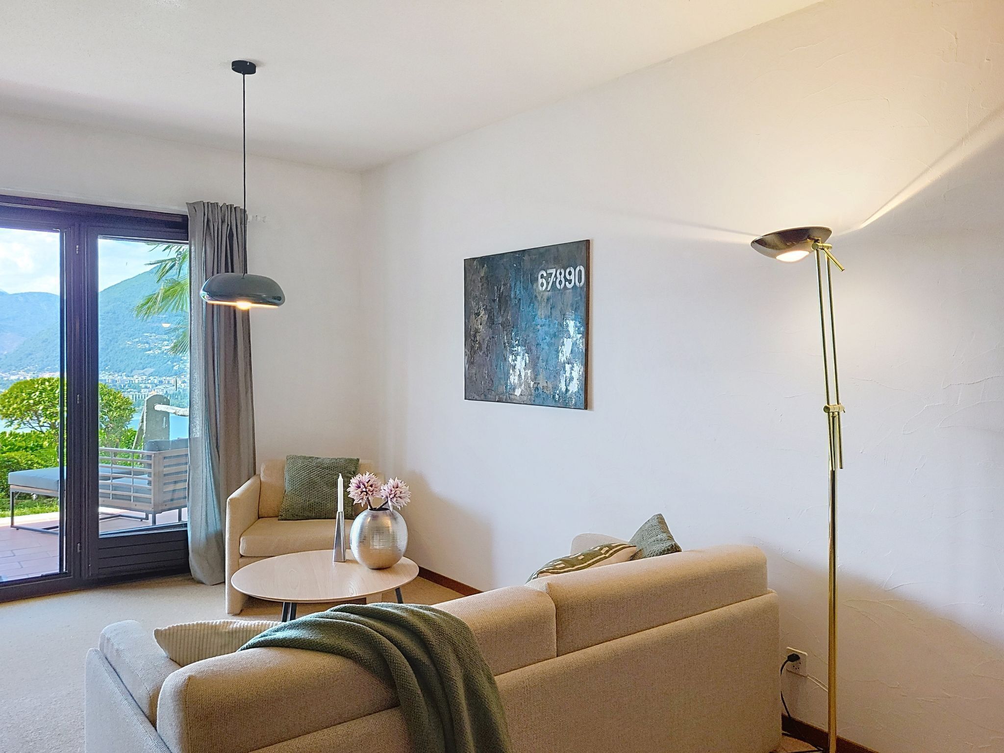 Una sala de estar moderna con un sofá, una mesita redonda, una lámpara de pie y un cuadro en la pared.