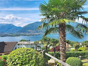 Un paysage côtier offrant une vue dégagée sur un lac, des montagnes et une zone résidentielle avec des maisons et de la verdure.