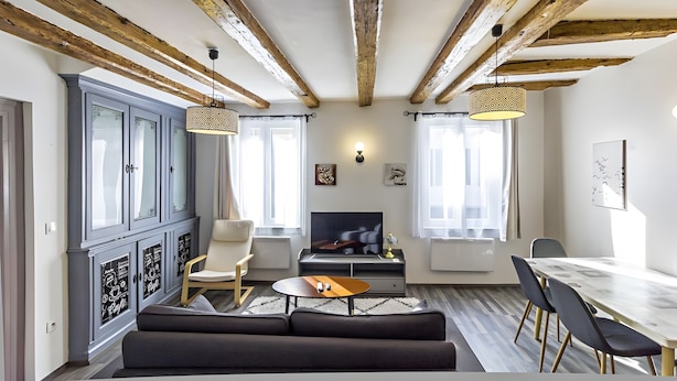 A modern living room with exposed wooden beams, a fireplace, a television, and a dining area.