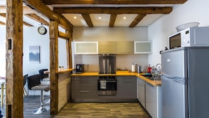 A modern kitchen with wooden beams, stainless steel appliances, and a wooden floor.
