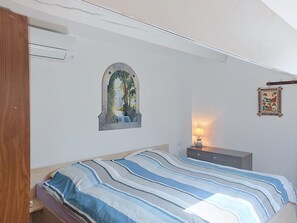 Un dormitorio con una cama, un cuadro en la pared, una lámpara de noche y una puerta de madera.