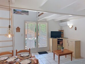 A compact living space with a dining area, a television, and a kitchenette. - Les Villas sur la Colline by Interhome (Narbonne-Plage)