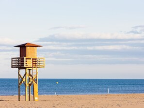 Ein hölzerner Rettungsturm am Strand bei blauem Himmel.